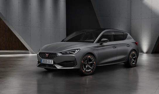 Der CUPRA Leon in dunkelgrau vor grauen Betonwänden.