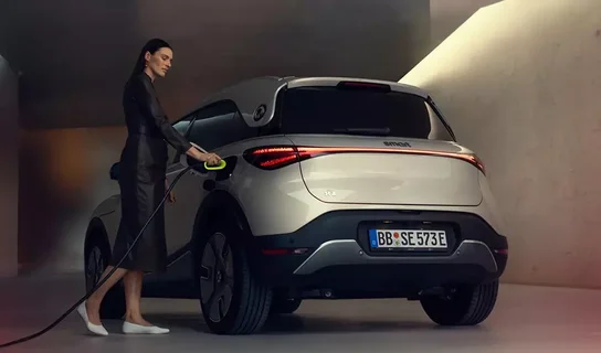 Ein weißer smart #1 wird von einer Frau in einem dunklen Kostüm geladen.